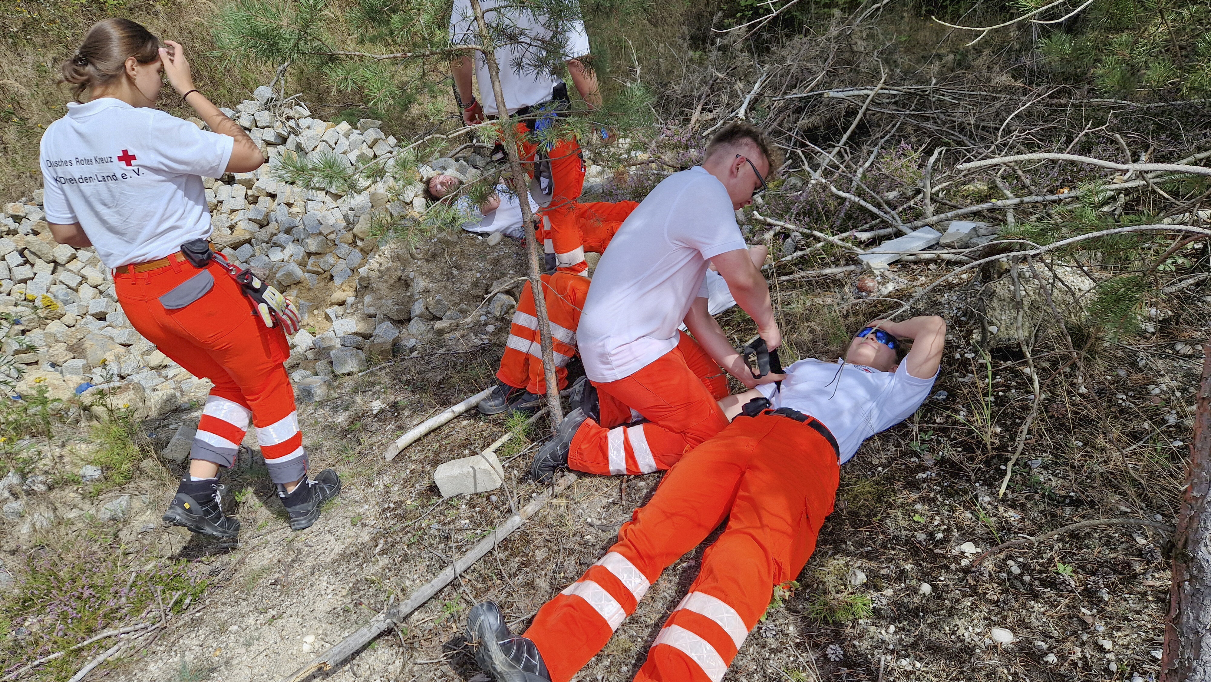 DRK-Einsatzkräfte beim Anlegen von Tourniqeuts in steinigem Gelände